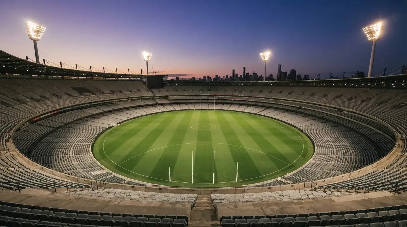 An empty football stadium with floodlight masts at dusk