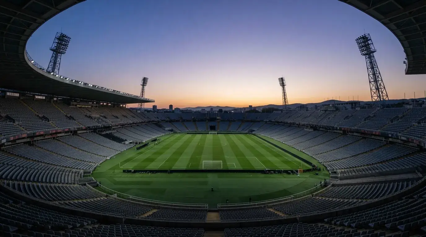 An empty football stadium with floodlight masts at dusk