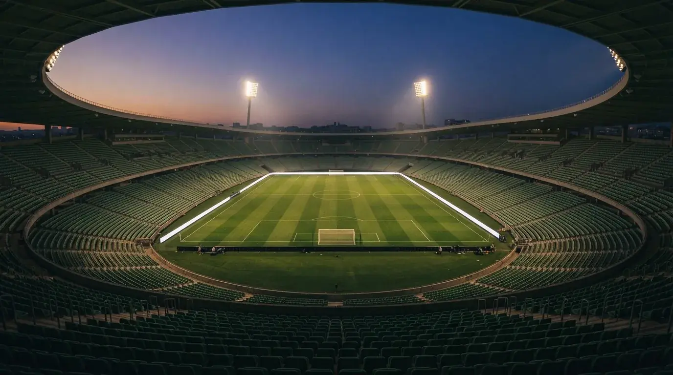 An empty football stadium with floodlight masts at dusk