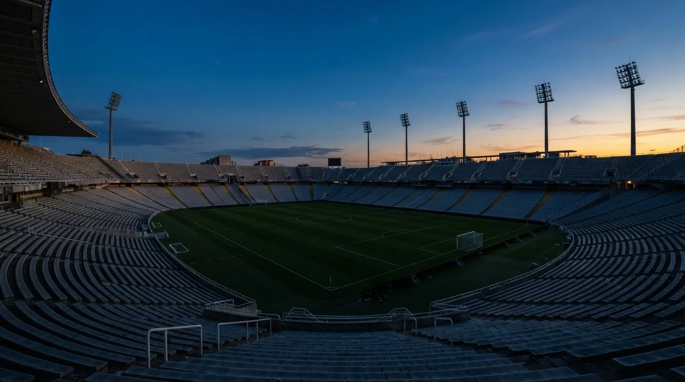 An empty football stadium with floodlight masts at dusk