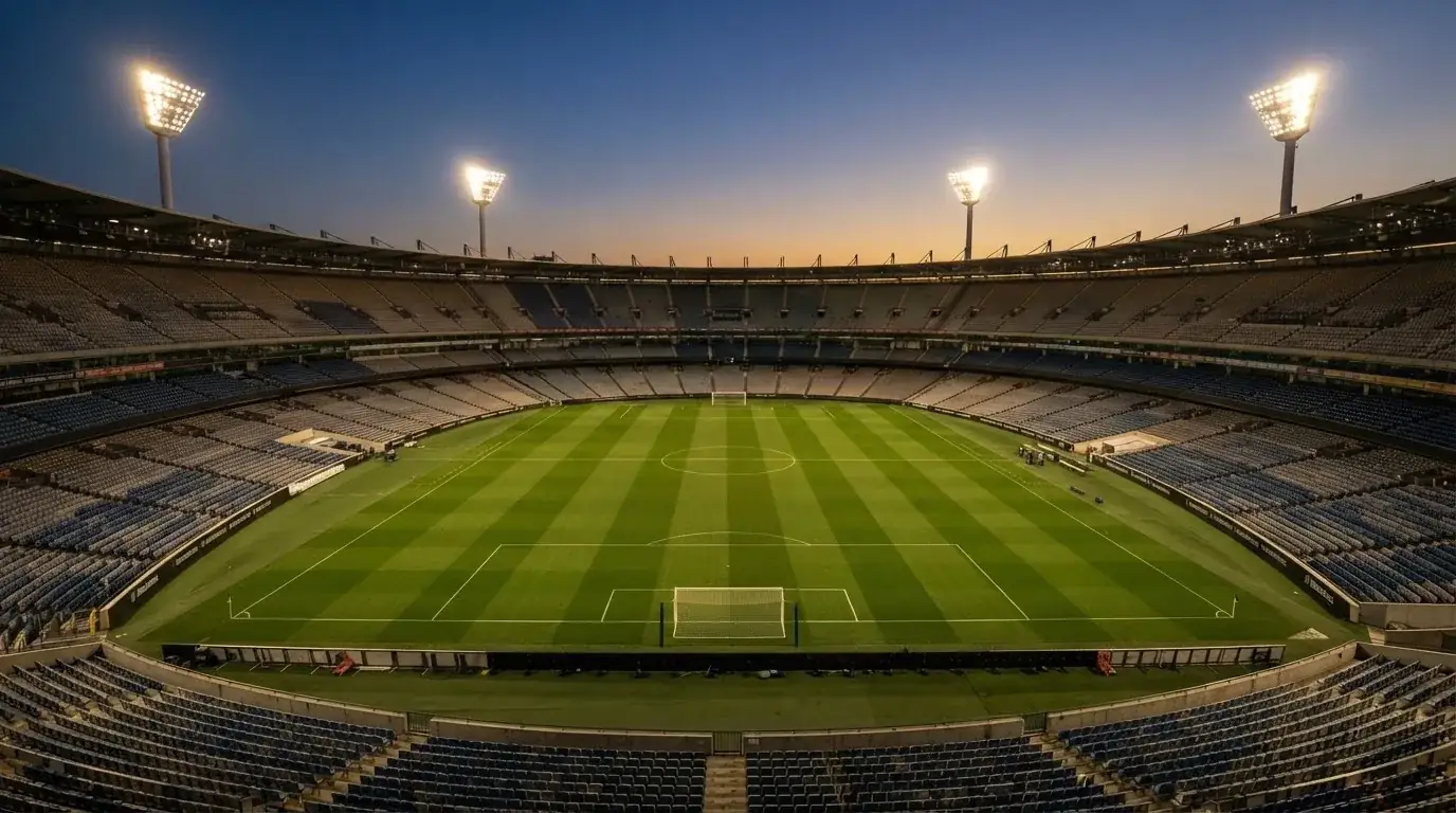 An empty football stadium with floodlight masts at dusk