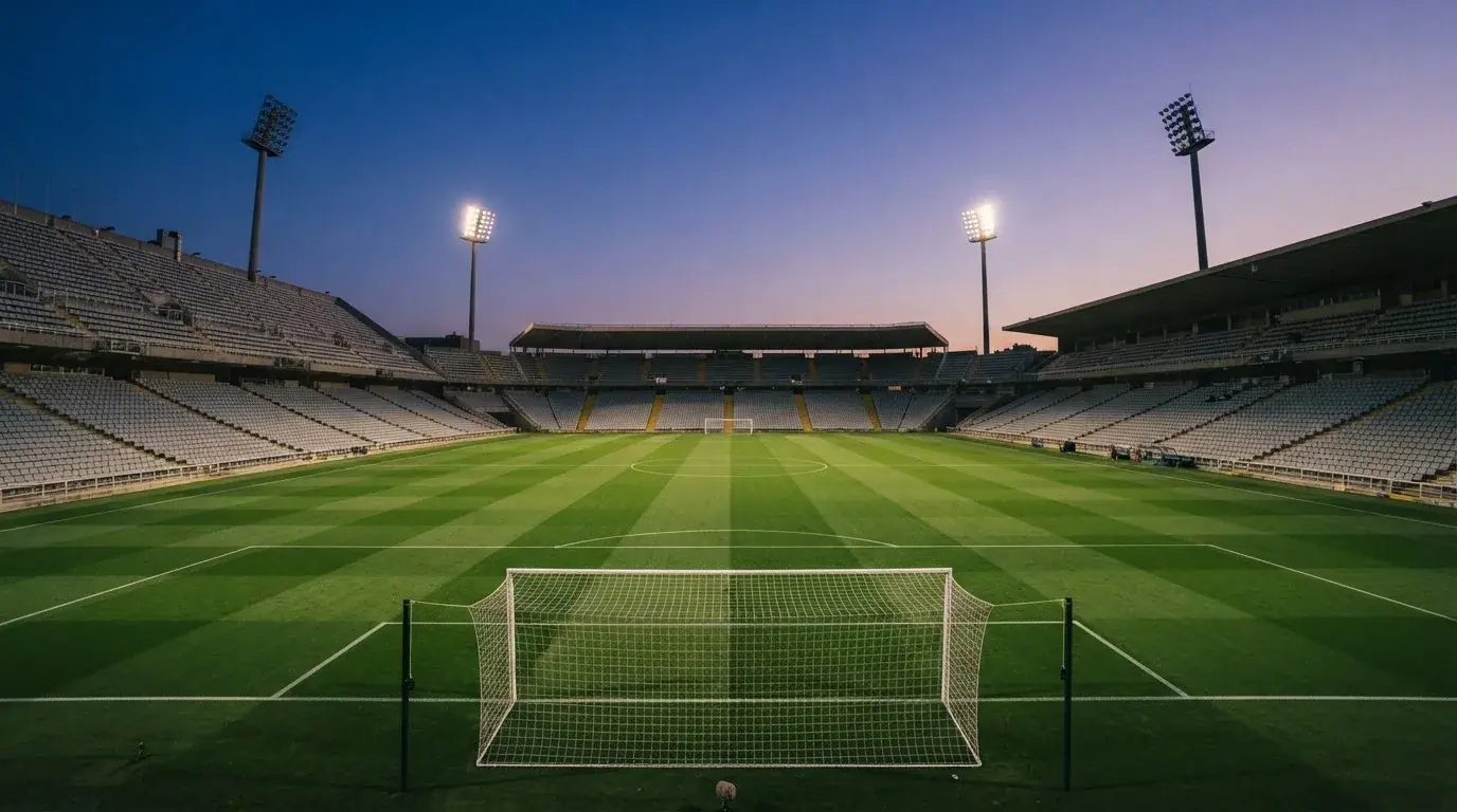 An empty football stadium with floodlight masts at dusk