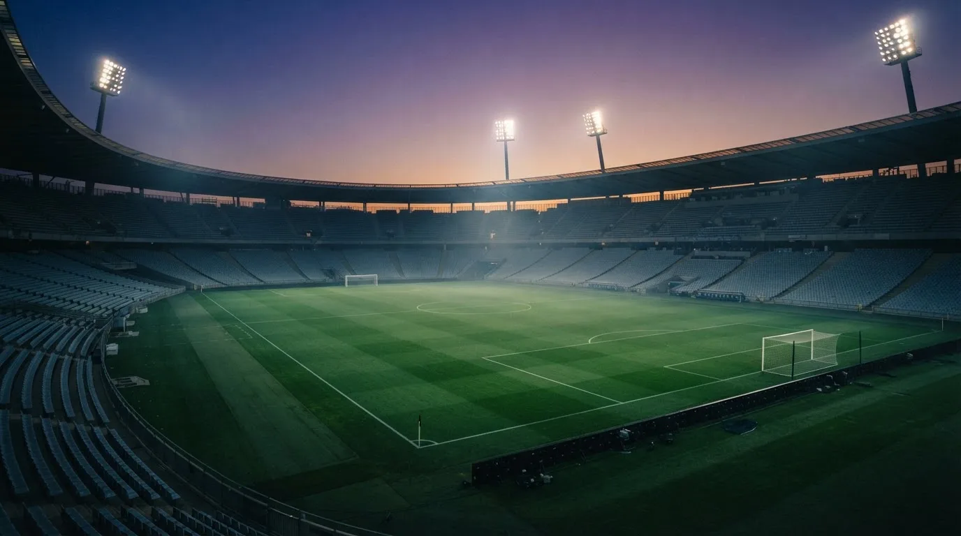 An empty football stadium with floodlight masts at dusk