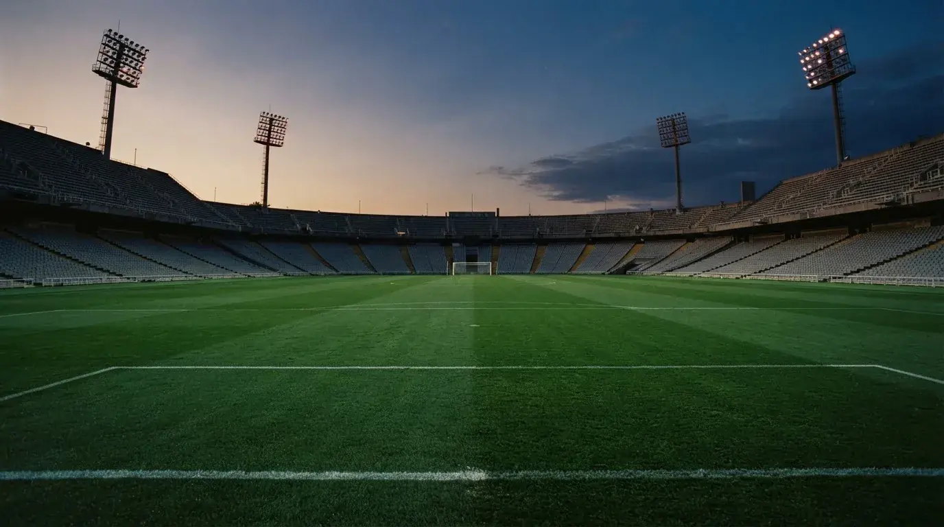 An empty football stadium with floodlight masts at dusk