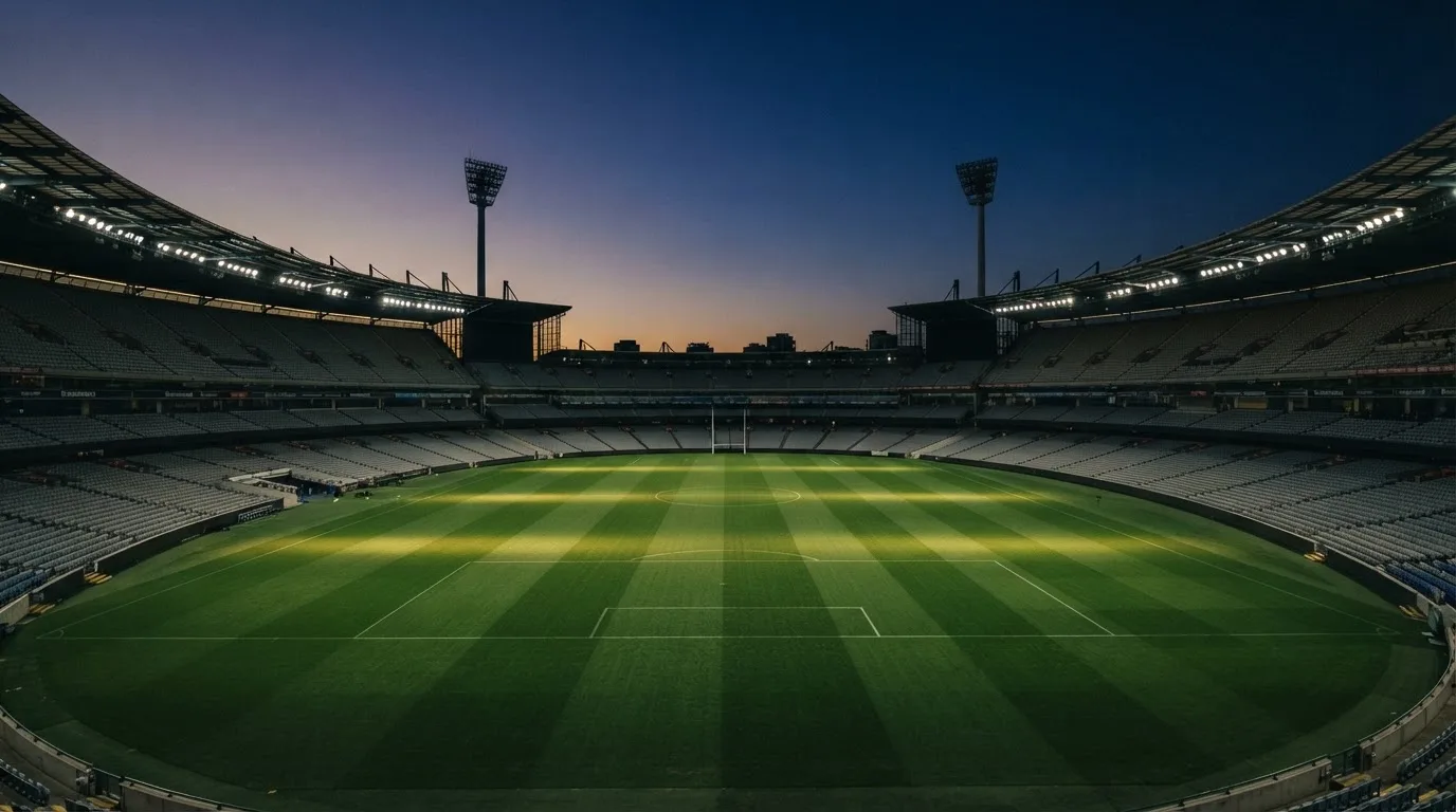An empty football stadium with floodlight masts at dusk
