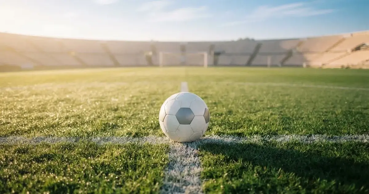 A ball on the centre spot of a grass pitch in morning light