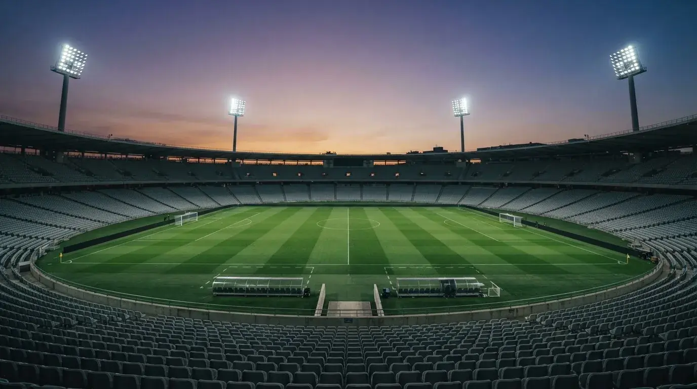 An empty football stadium with floodlight masts at dusk