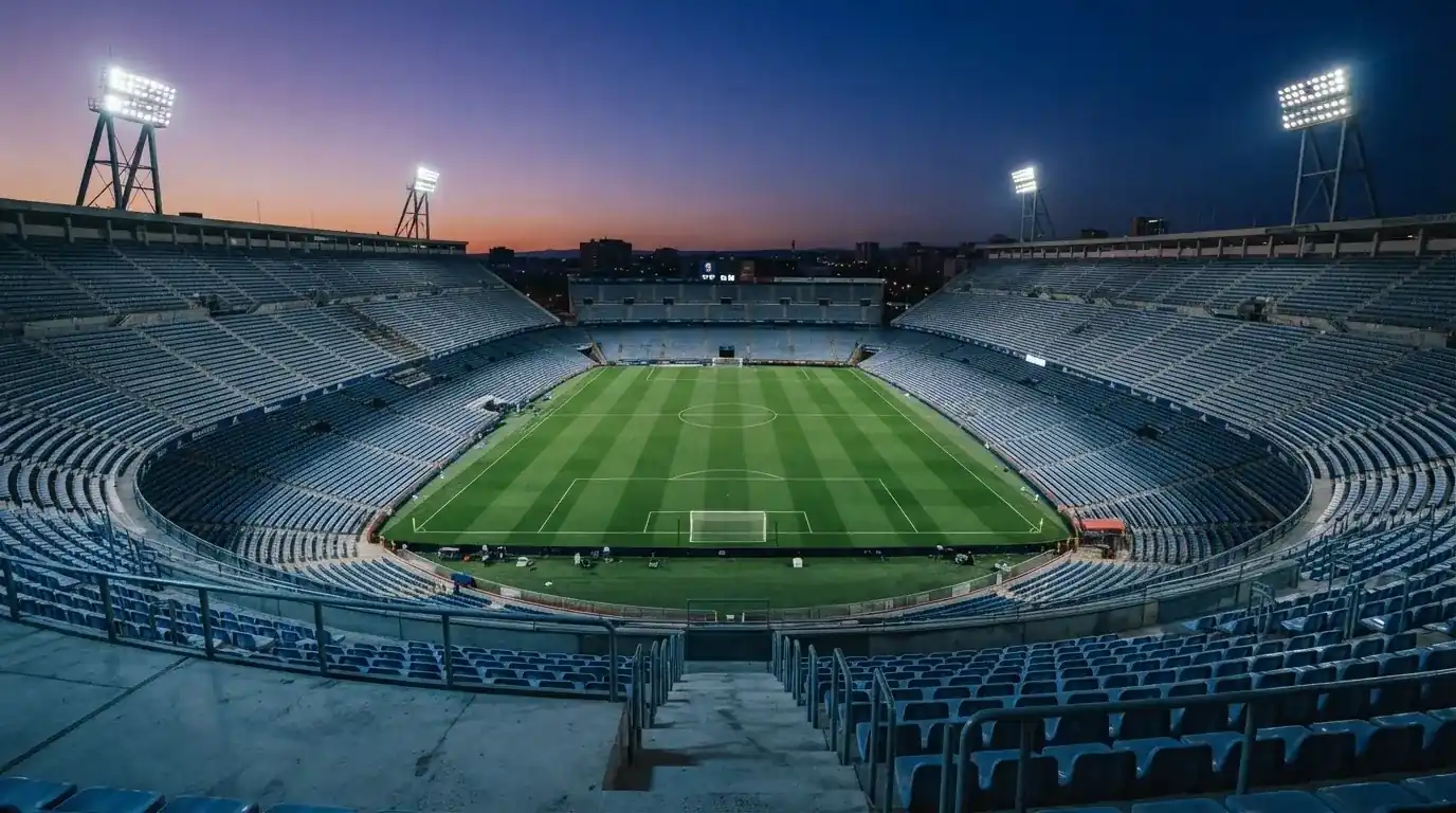 An empty football stadium with floodlight masts at dusk