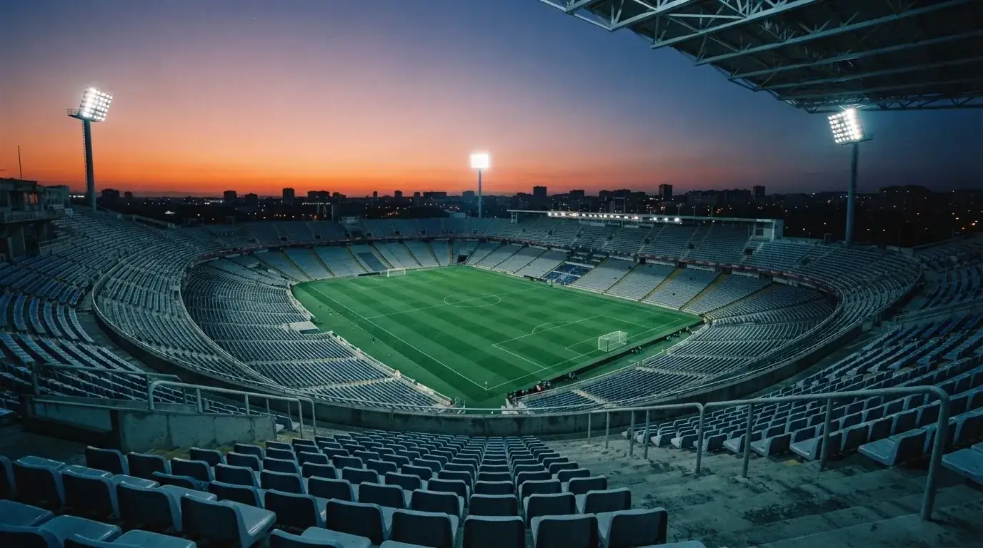An empty football stadium with floodlight masts at dusk