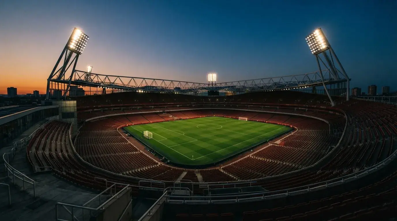 An empty football stadium with floodlight masts at dusk