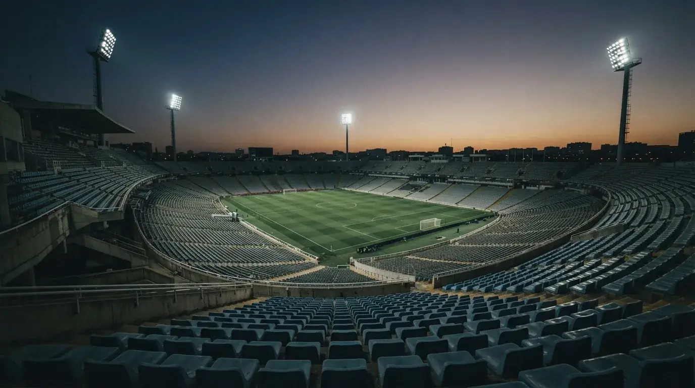 An empty football stadium with floodlight masts at dusk