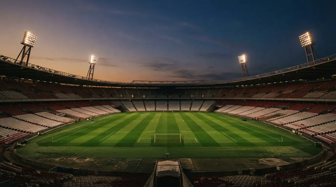 An empty football stadium with floodlight masts at dusk