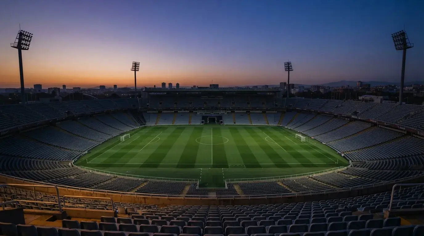 An empty football stadium with floodlight masts at dusk