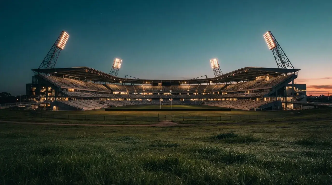 An empty football stadium with floodlight masts at dusk