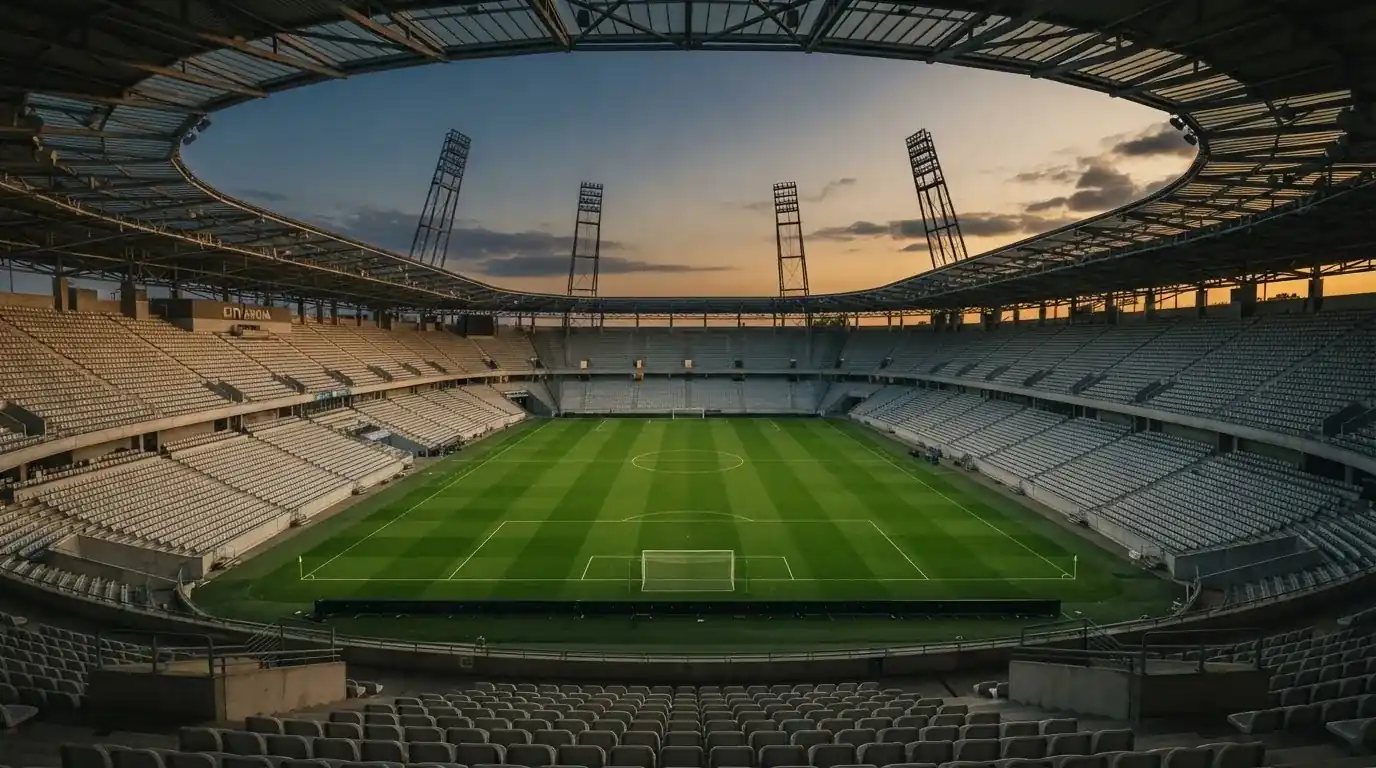 An empty football stadium with floodlight masts at dusk